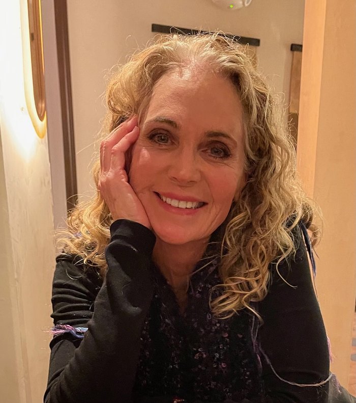 Portrait of Ché Leone smiling, resting her hand against her cheek